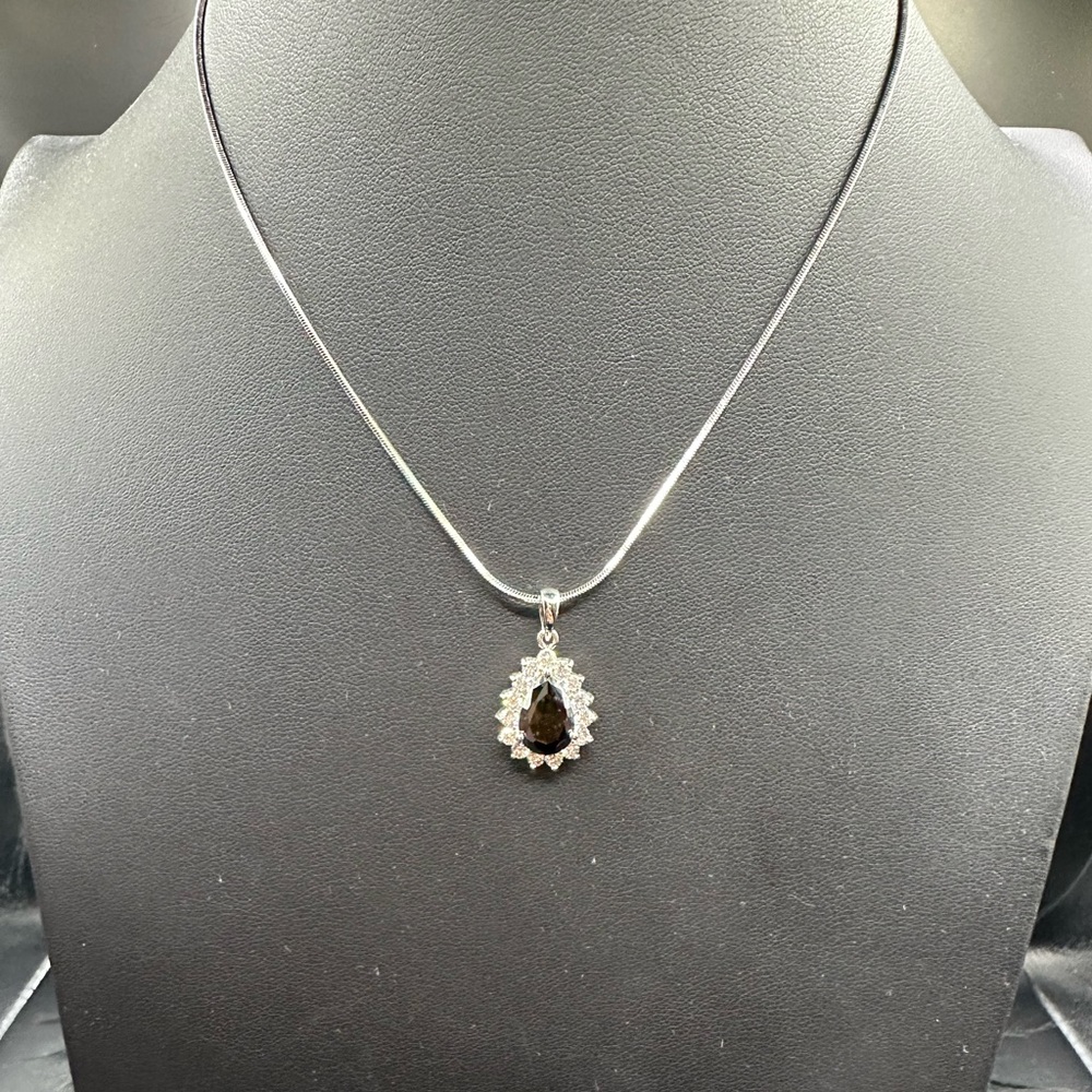 Black teardrop stone surrounded by clear crystals on a silver chain.